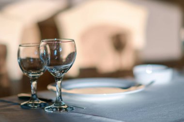 Beyaz masada boş şarap bardakları. Arka planı aydınlanmış, seçici odaklı.