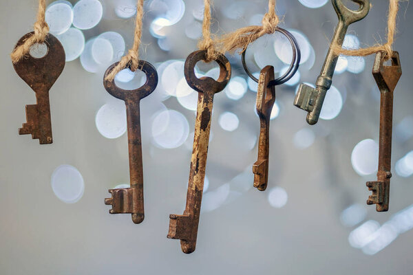 Old rusty keys hanged on the ropes with blurred lights soft background, selective focus