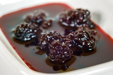 Beyaz tabaktaki böğürtlen reçelinin yakın görüntüsü.