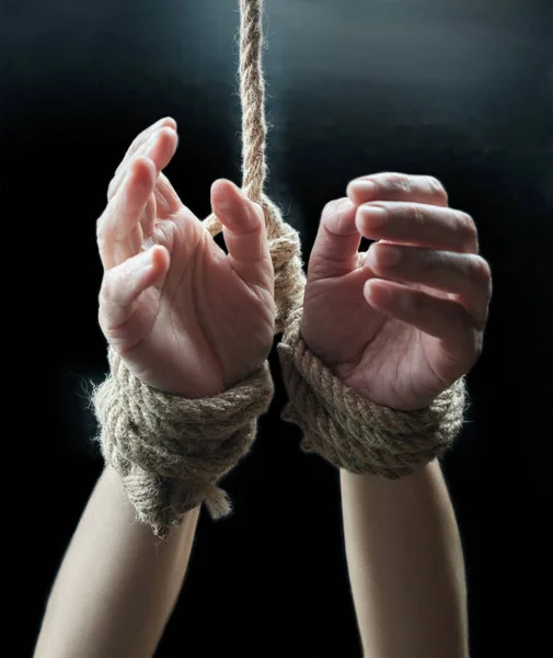 Hands of a victim woman tied up with rough rope on the black background. Stop abusing violence concept