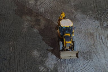 Çakıl taşlarının üzerinde bir gece boyunca gölgeli sarı traktör