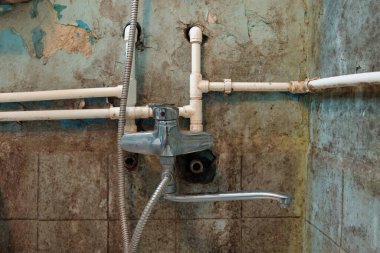 Eski musluk ya da lavabo ve paslı borular kirli bir duvarda.