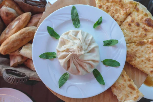 Bir büyük Khinkali (Gürcistan hamur tatlısı) beyaz tabakta nane yaprakları, üst görünüm  