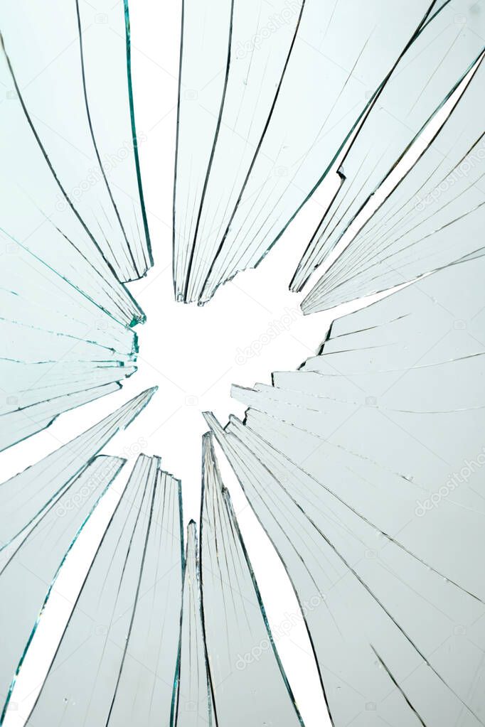 Closeup of broken and cracked glass with hole on a white background