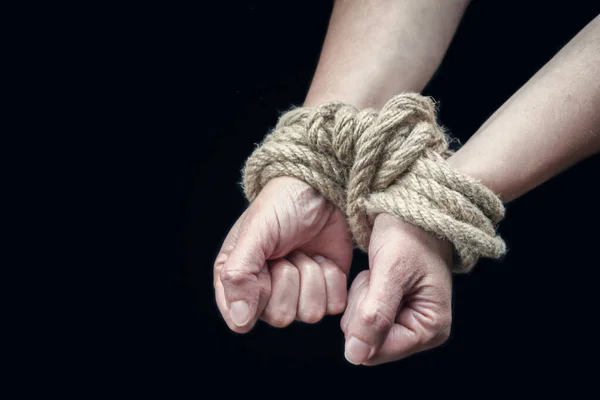 Hands of a victim woman tied up with rough rope on the black background. Stop abusing violence concept