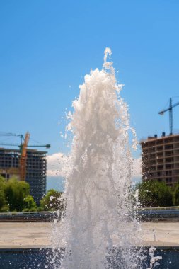 Kasaba meydanında mavi gökyüzü arka planlı bir çeşmenin su sıçratması ve akışı.