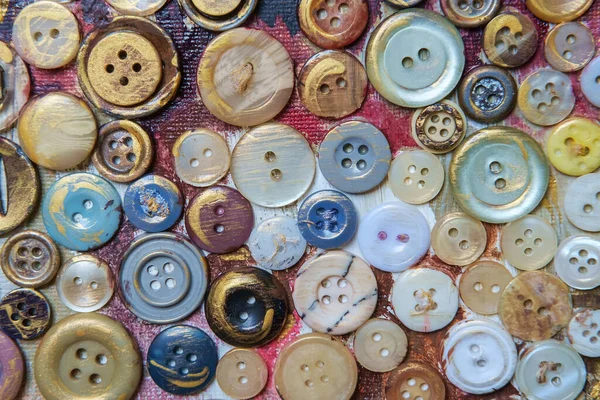 Different color buttons for clothes on a painted surface. Close-up