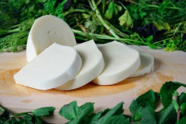 Tahtada dilimlenmiş peynir ve yeşil otlar. Gürcistan peyniri sulguni