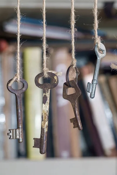 Oude Roestige Toetsen Opgehangen Aan Touwen Met Wazig Boek Plank — Stockfoto