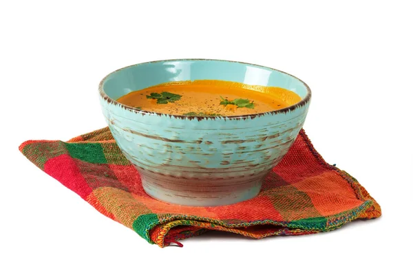 白い背景に隔離されたカラフルなテーブルクロスの上のボウルにカボチャのスープ — ストック写真