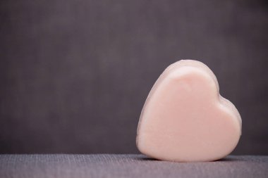 Sabun yürekten pembe veya kahverengi gri arka plan üzerine de mum balmumu. Sevgililer günün kutlu olsun. Kopya alanı.