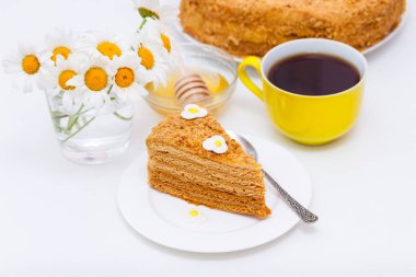 Çay veya kahve ve chamomiles sarı fincan ile ev yapımı katmanları bal kek Dilim.