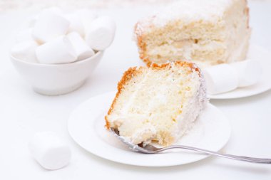 Beyaz krem ve Hindistan cevizi yongaları ile pasta bir parça, plaka üzerinde Marshmallow