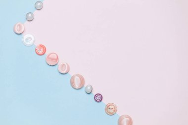 Düğmeler, pastel pembe ve mavi arka plan üzerinde dikiş ve iğne için aksesuarlar. Kopyalama alanı, düz yatıyordu.