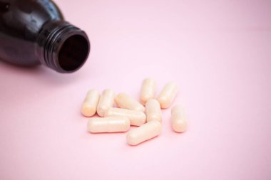 Pembe arka planda bitkisel doğal kapsüller. Kadın sağlığı kavramı.