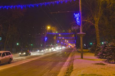 Akşam kış şehir sokak aydınlatma fener ışığında. Sokak yeni yıl için dekore edilmiştir.