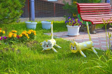 Odun ve çöp kalıntılarından hayvan (kedi) figürleri çiçek yatağını süslüyor