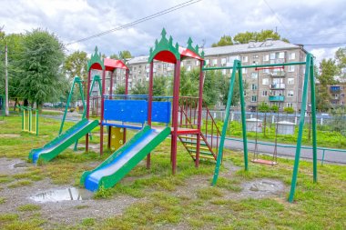 Bir apartmanın her zamanki avlusunda yağmurdan sonra çocuk oyun alanı. taşra kasabası. Yaz. Rusya