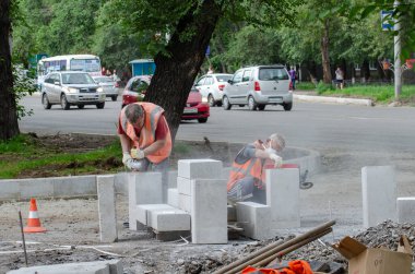 Yol işçileri yolda yeni bir kaldırım taşı işleyip istiflediler.
