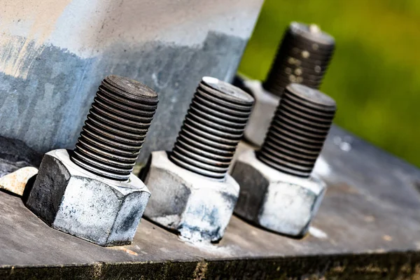 Huge bolts and nuts together in a flange fastening a giant pole in the air