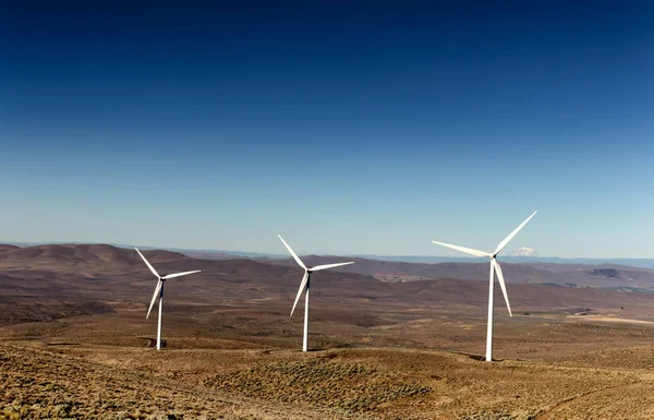 Green sustainable energy windmill power turbine electricity generators on rolling hills with clouds and blue sky above