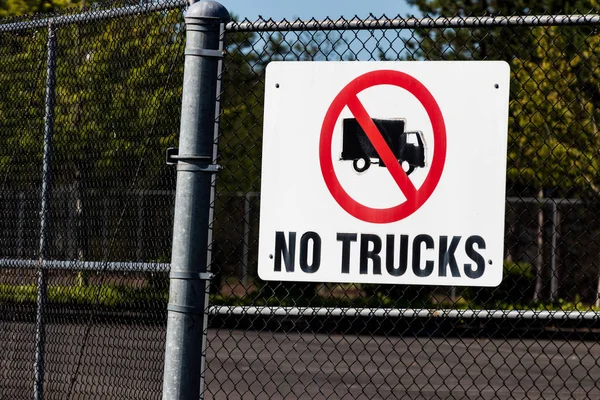 White no trucks sign on a chain link fence gate