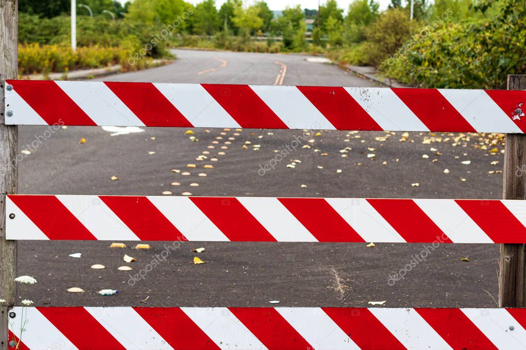 Road block barricade sign stripes white and red with road behind