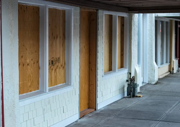 Retail storefront closed and boarded up with plywood