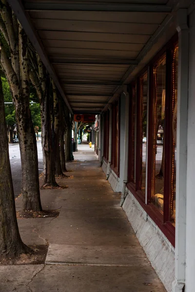 Empty retail storefront covered sidewalk with trees