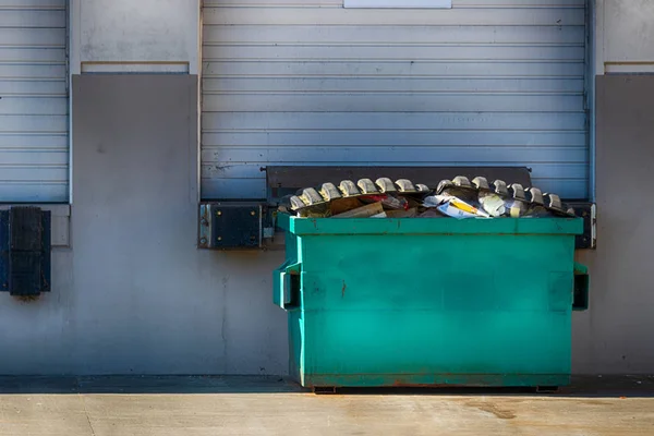 Außenwand des Lagers mit Garagentor und Müllcontainer Stockfoto