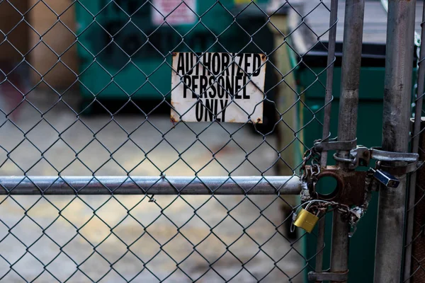 Firma de personal autorizado en una cerca de eslabones de cadena con contenedores de basura — Foto de Stock
