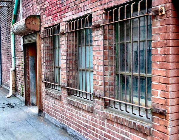 Perspektiva stará cihlová budova s ocelovými mřížemi — Stock fotografie
