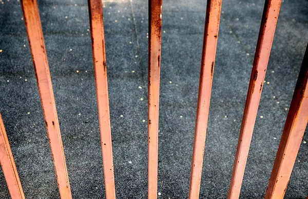Cerca enferrujada abstrata olhando sobre concreto — Fotografia de Stock