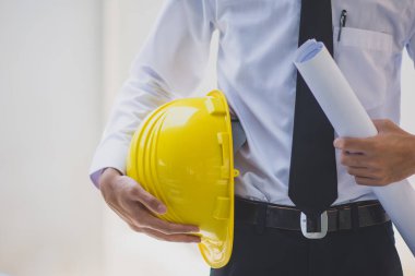 Miğfer tutan mühendis, inşaat işiyle uğraşıyor.