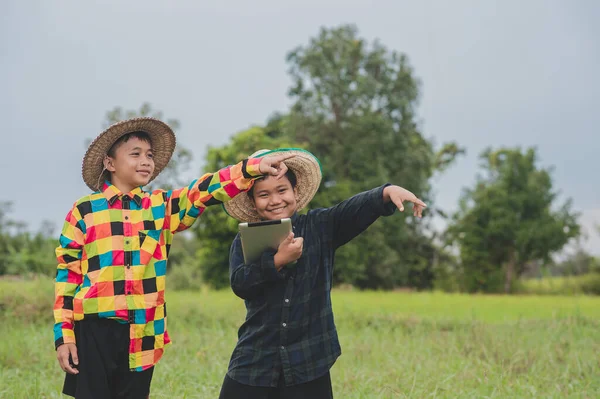 Two boy Asian people using tablet standing out door farmer,Concept Smart farmer or Education collage study school