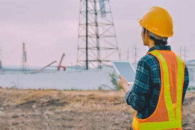 Tablet tutan mühendis inşaat teftişinde çalışıyor.