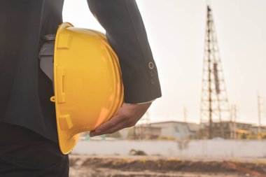 Kapalı proje yöneticisi miğfer sabit başlıklı inşaat arka planını tutuyor