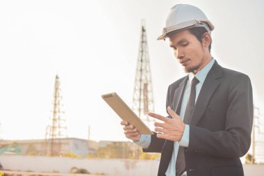 Site inşaatında çalışan ve tablet mobil internet teknolojisi kullanan adam, iş kavramı