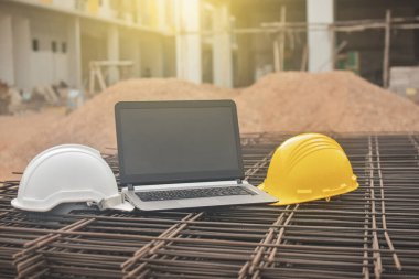 Bilgisayar not defteri Sarı kask ve Whit miğfer çelik bina inşaatı üzerine