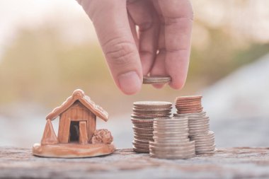 Elle seçilen madeni paralar ev modelini ahşap masaya dizer