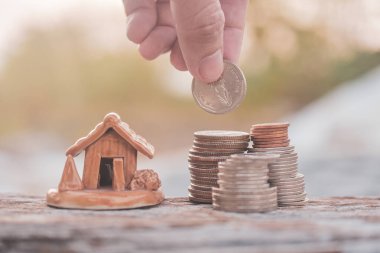 Elle seçilen madeni paralar ev modelini ahşap masaya dizer