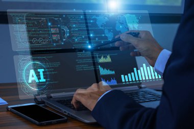 Bir iş adamının elleri yapay zeka sistemini kontrol etmek ve finansal verileri analiz etmek için telefon ve laptop kullanıyor.