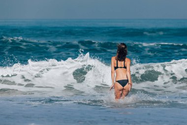 Genç kadın siyah bikini denize yürüyüş 