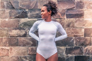 Afro american model in white bikini against brick wall clipart