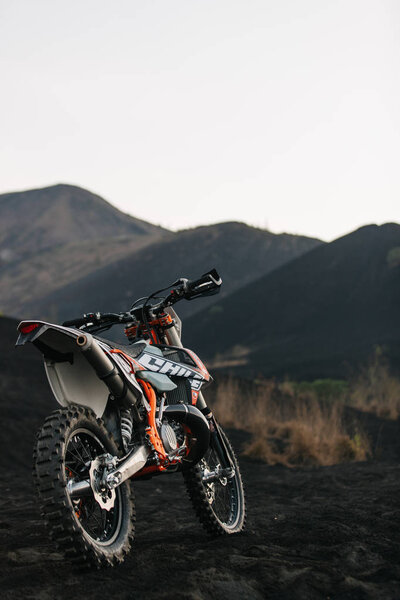 Dirt motocross enduro motorcycle ready for race on the black lava at sunrise on mount Batur, Bali, Indonesia