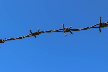 Rusty dikenli tel çit açık mavi gökyüzü arka planda
