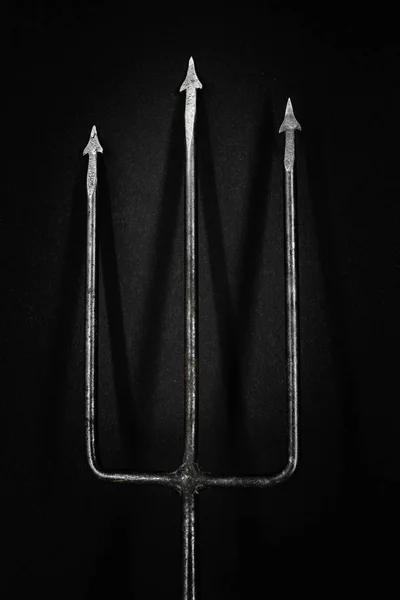 Siyah arka plan yüzeyi gölgesi vuran eski, paslı ve metal trident