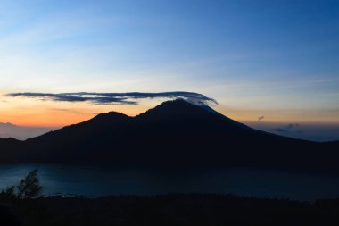 Gunung Batur yanardağ Bali, Endonezya Mount Agung Yanardağı tepe görünür silueti ile gündoğumu görünümünden bulutları ile örtülü