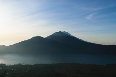 Gunung Batur yanardağ Bali, Endonezya Mount Agung Yanardağı tepe görünür silueti ile gündoğumu görünümünden bulutlar ve sis ile kaplı