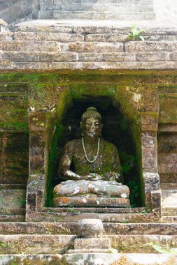 Buda oturan çok eski taş heykel yosun ve likenler ile kaplı ve inci kolye ile dekore edilmiş